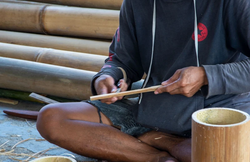 An artisan splitting cane into thin strips for weaving